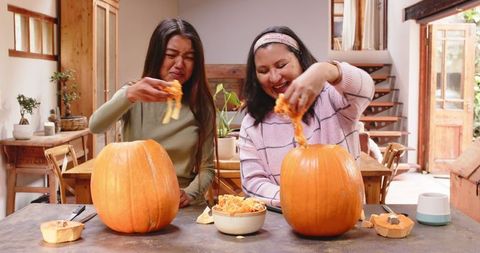 Grandmother and Young Woman Carving Pumpkins for Halloween Celebration