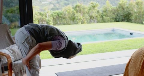 Asian male stretching indoors with pool view for relaxation