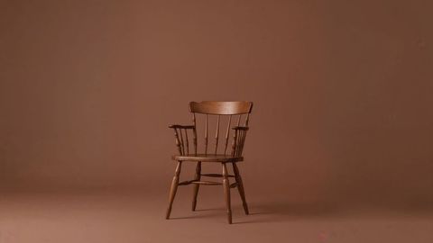 Vintage wooden spindle-back armchair against brown background