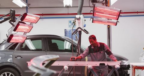Mechanic working in auto repair workshop with grinding tools