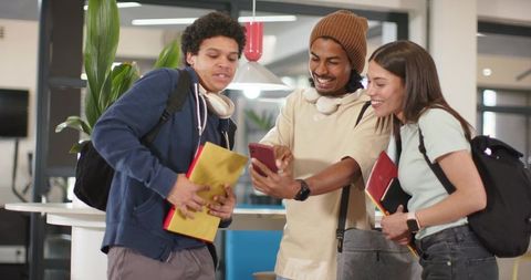 African american students sharing smartphone and studying together in campus lounge
