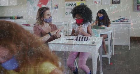 Teacher and students in classroom with mathematical overlay during pandemic