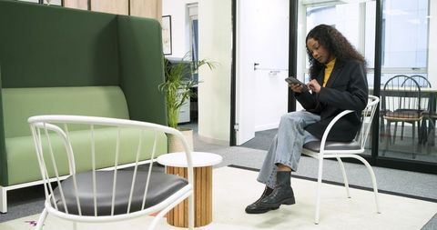 Businesswoman Relaxing with Smartphone in Modern Office Lounge