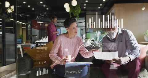 Team reviewing interactive data visualizations on glass screen in modern office lounge