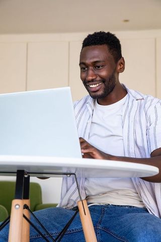Man smiling while working remotely on laptop at home