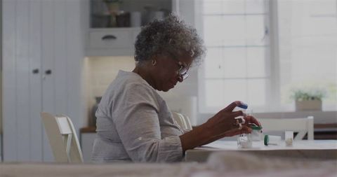 Senior african american woman organizing pills in kitchen