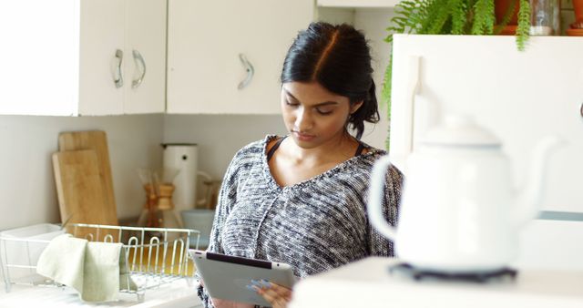 Woman using digital tablet in kitchen at home