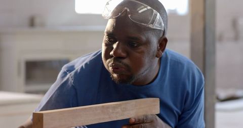Senior craftsman inspecting wood in renovation workshop