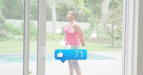 Woman stretching on backyard pool deck through sliding glass door with social like notifications
