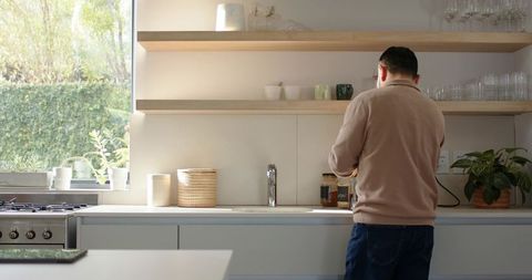 Asian Man Making Coffee in Minimalist Bright Kitchen