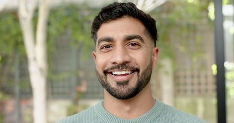Smiling Man in Garden with Mint Green Sweater Looking Relaxed