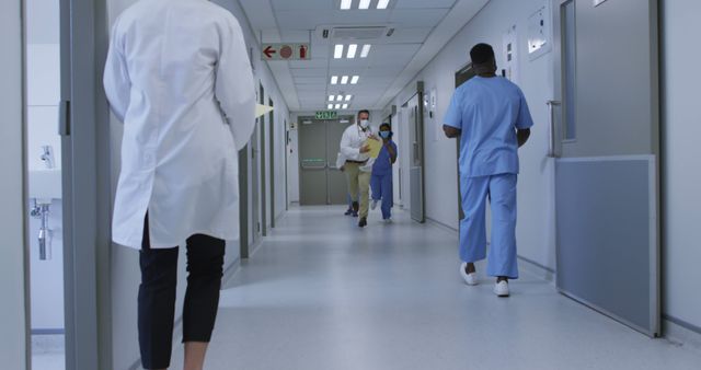 Diverse group of male and female doctors in face masks running through hospital corridor - Download Free Stock Photos Pikwizard.com