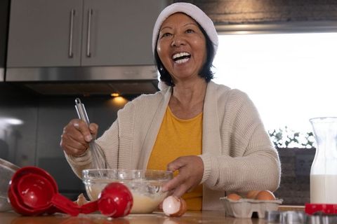 Joyful Senior Asian Woman Baking in Festive Kitchen
