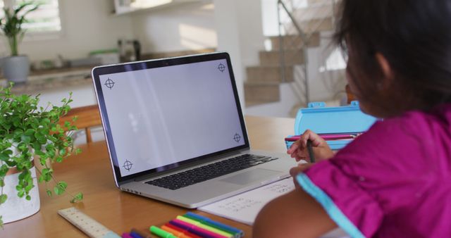 Hispanic girl sitting at table using laptop drawing. at home in isolation during quarantine lockdown.