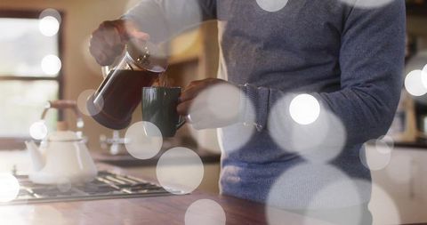 Senior Man Pouring Coffee from French Press at Kitchen Island