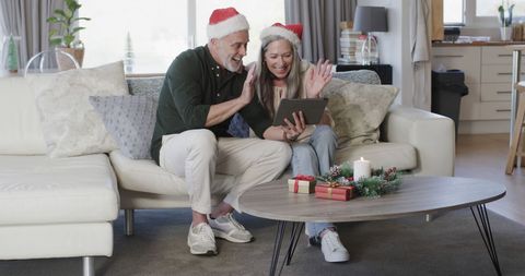 Middle-Aged Couple in Santa Hats Video Chatting at Home During Christmas