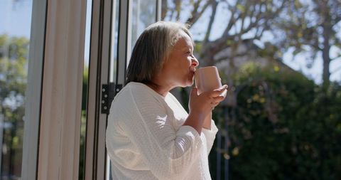 Senior Woman Enjoying Morning Coffee by Sunny Window