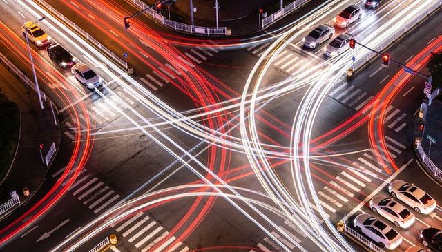 Aerial long-exposure intersection light trails forming dynamic red and white traffic flows