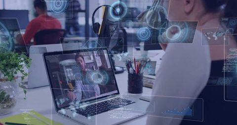 Asian woman watching video call on laptop with augmented reality overlays in open office