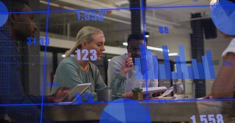 Midadult blonde woman pointing at tablet while team collaborating on data with charts