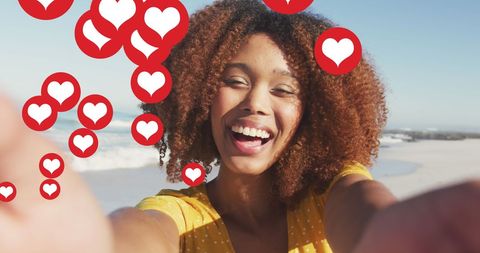 Joyful woman taking selfie with floating love hearts outdoors