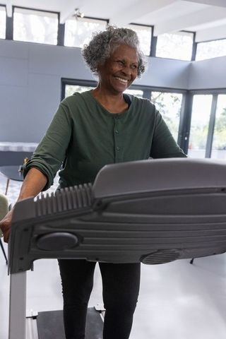 Senior African American Woman Exercising on Treadmill in Modern Fitness Center