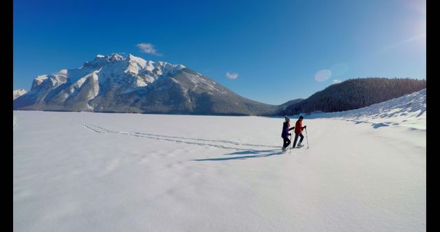 Couple Snowshoeing on Vast Snow-Covered Landscape with Majestic Mountain Backdrop - Download Free Stock Images Pikwizard.com