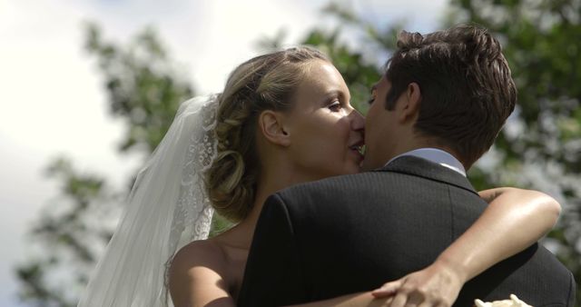 Bride and groom kissing each other outside on their wedding day
