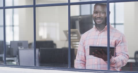 Smiling Businessman Holding Tablet Near Office Window