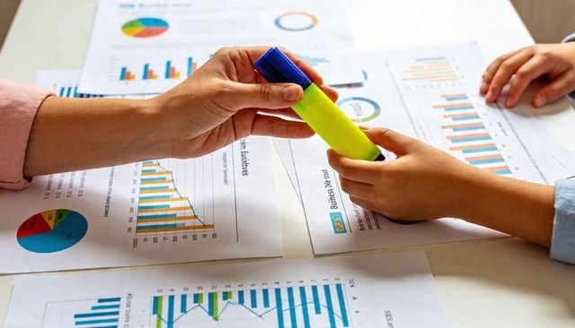 Adult and child passing yellow highlighter over printed charts for collaborative learning