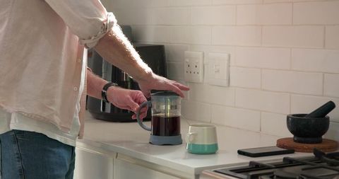 Man Brewing Coffee with French Press in Modern Kitchen