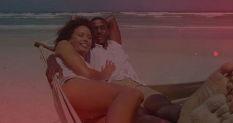 Couple Relaxing on Hammock by Ocean on Sunny Beach Day