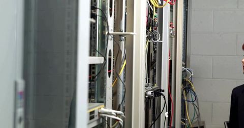 Engineer inspecting server rack with dense network cables in modern data center aisle
