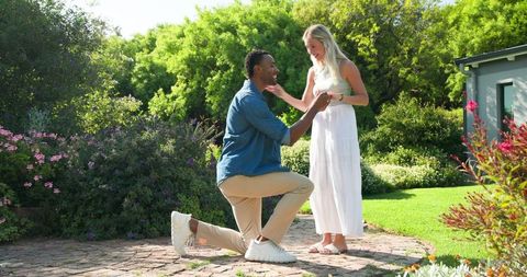 Joyful marriage proposal in sunlit garden setting