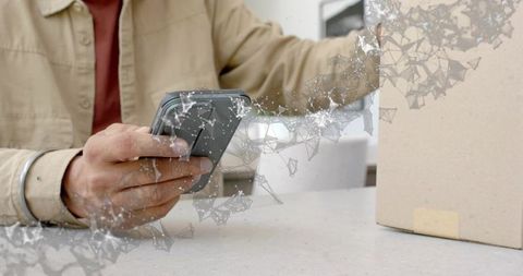 Man tapping smartphone beside cardboard package on counter with digital network overlay for tracking
