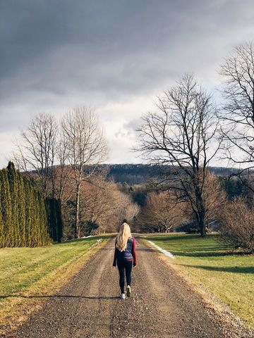 Woman Walking on Rural Path in Early Spring