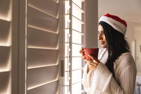 Festive Woman with Red Mug Enjoying Cozy View During Holidays