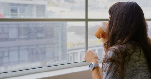 Businesswoman Relaxing with Coffee near Office Window