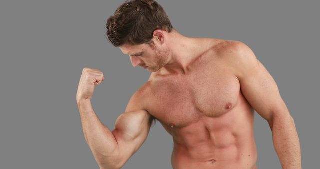 A young Caucasian man is flexing his bicep, showcasing his muscular physique, with copy space - Download Free Stock Photos Pikwizard.com