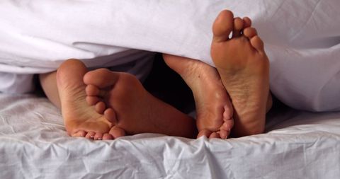 Playful Feet Wiggling Under Warm Blanket in Bedroom