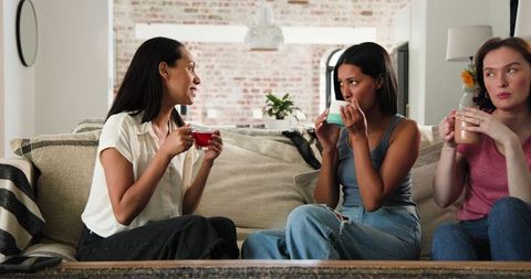 Happy Friends Enjoying Tea Discussing Pregnancy News in Sunny Living Room
