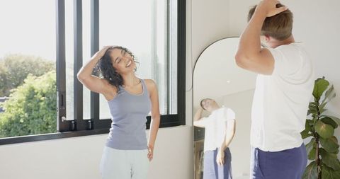 Couple neck stretching exercise at home in sunlit room
