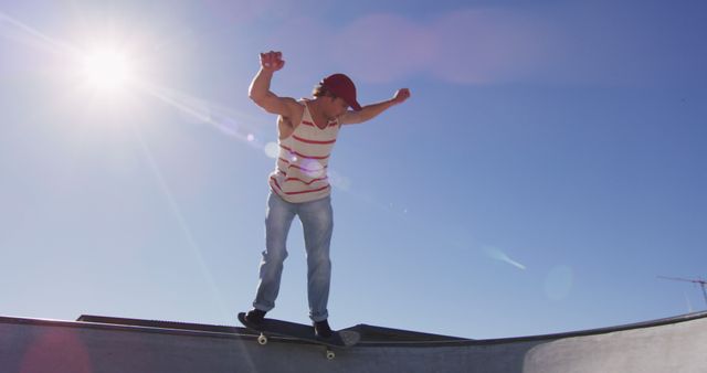 Young skateboarder is performing tricks at a skatepark on a sunny day, wearing a red hat and casual clothing. This visual emphasizes skill, action, and modern skate culture. Ideal for promoting extreme sports, outdoor activities, skateboarding products or highlighting active, youthful lifestyles.