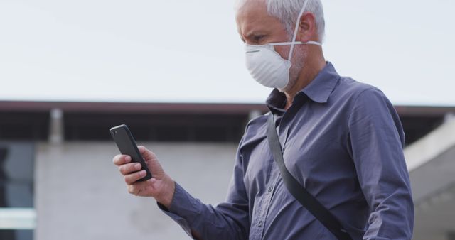 Mature man wearing mask using smartphone outdoors - Download Free Stock Images Pikwizard.com