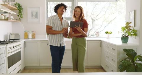 Diverse Couple Consulting Tablet in Bright Modern Kitchen