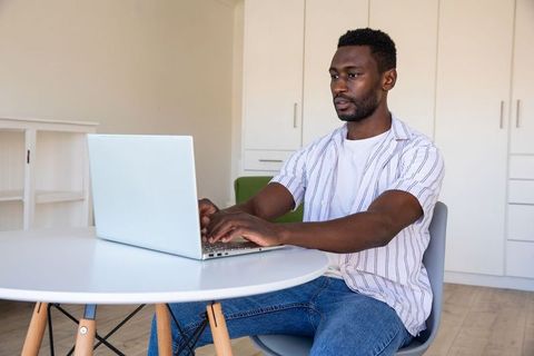 Focused Mid-Adult African American Man Working on Laptop at Home Office Desk