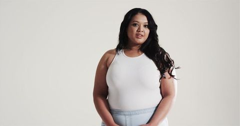 Confident woman in minimalistic attire with neutral backdrop