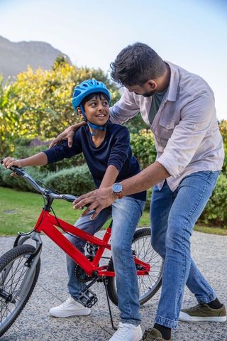 Father teaching son to ride bike on garden patio
