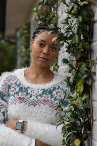 African american woman standing with arms crossed wearing fuzzy sweater and smartwatch