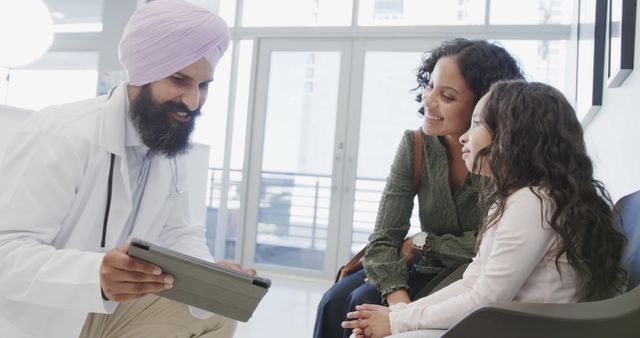 Smiling Doctor Using Tablet with Mother and Daughter in Waiting Room - Download Free Stock Images Pikwizard.com